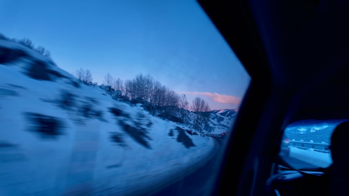 Blue winter light on snow-covered hills seen through a car's side window