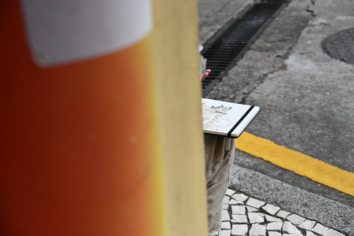 An orange foreground column beside patterned pavement and a yellow road marking