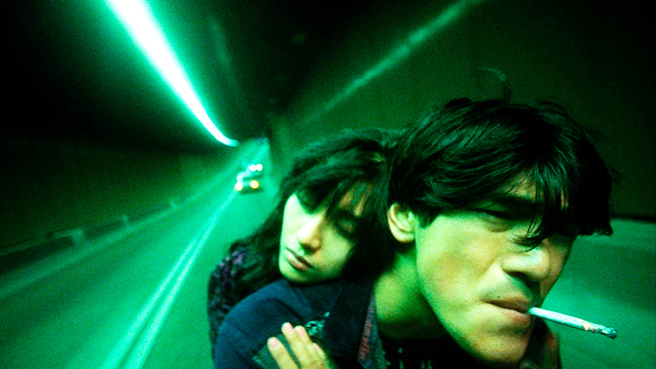 Two characters under green light in a distorted wide-angle frame from Fallen Angels